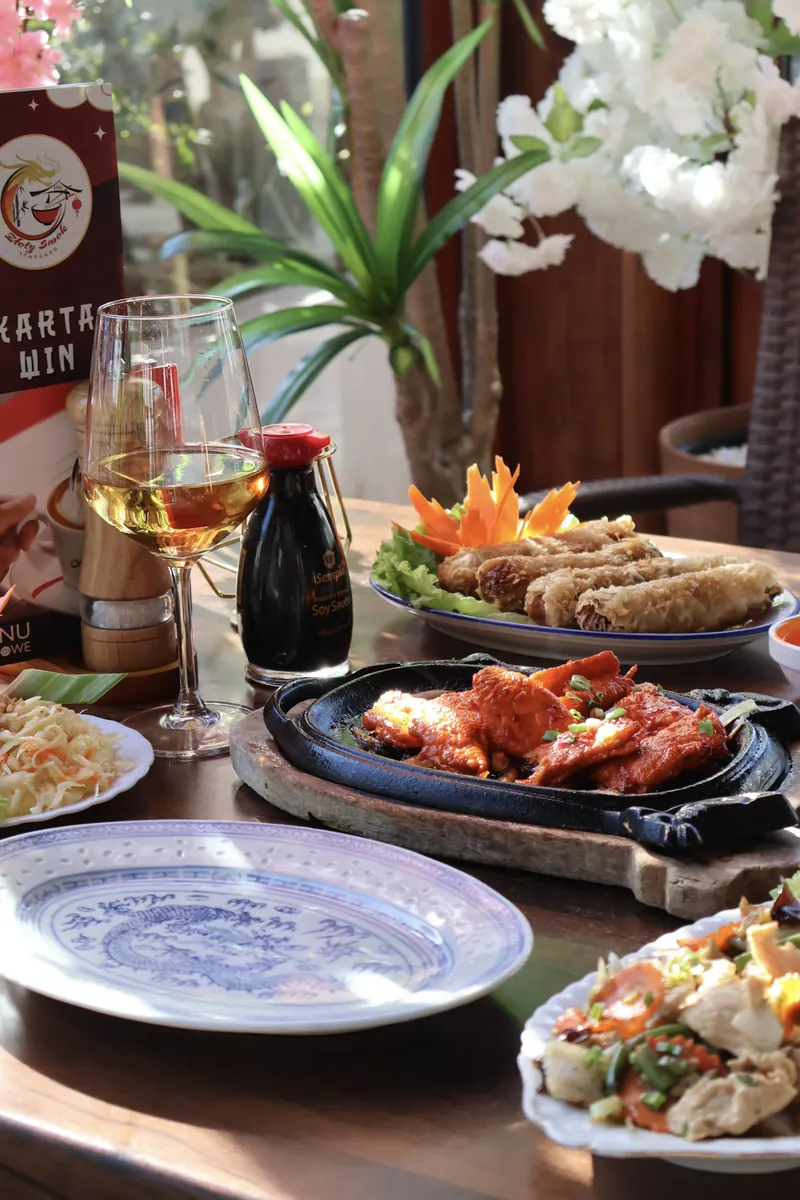 Zastawiony stół w restauracji: dania, kieliszek wina, kwiaty